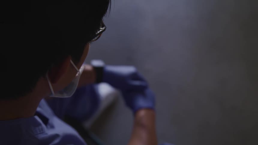 A doctor sits and looks down at the floor