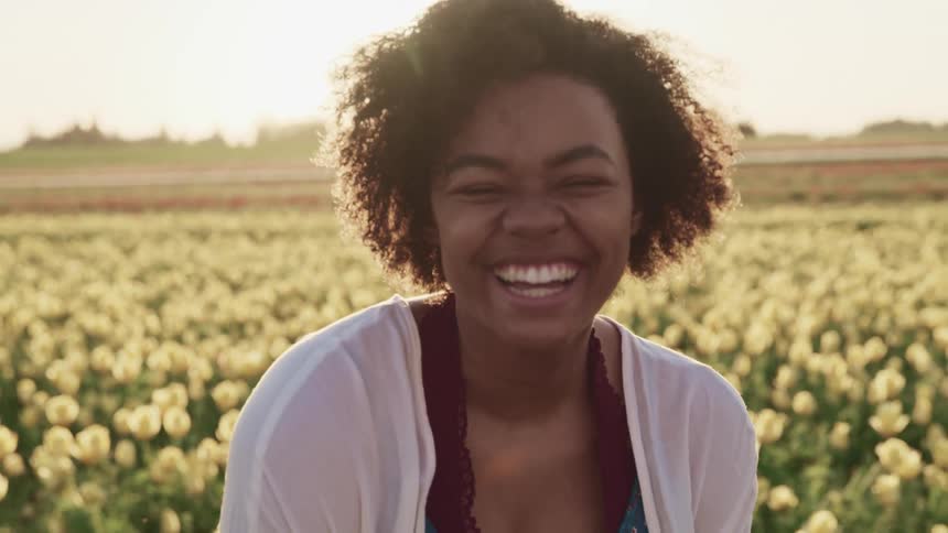 A woman in a field of flowers laughing