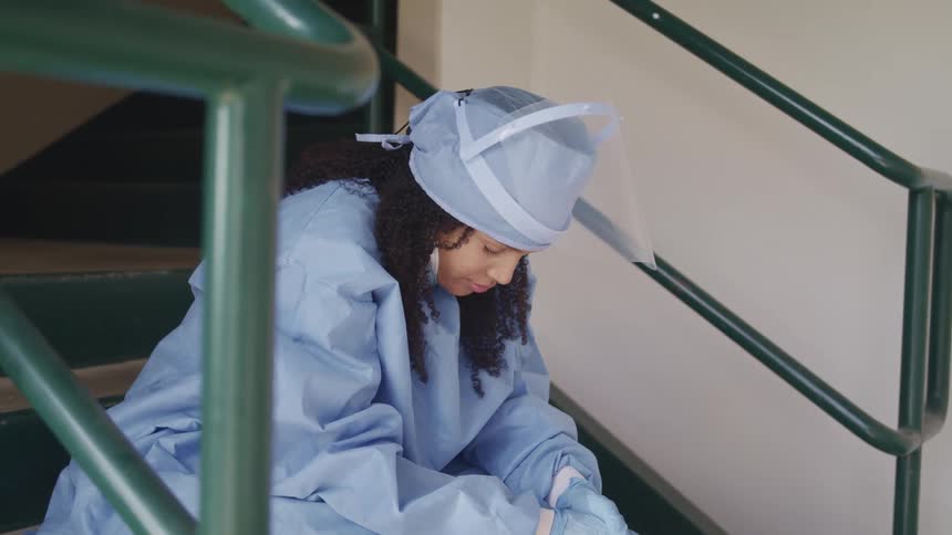 A nurse sitting in a stairwell drops her head down