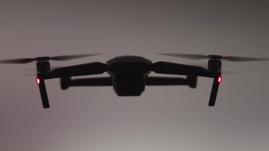 A four rotor drone hovers in the air