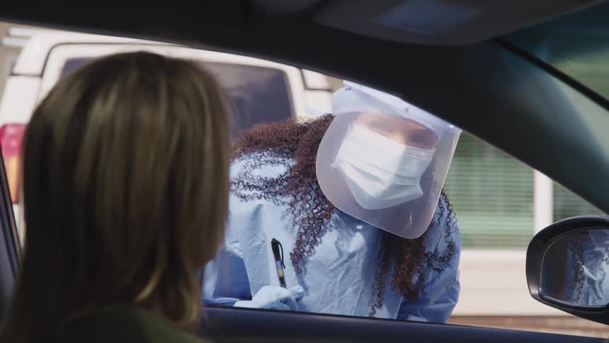 A person wearing protective equipment checks the interior of a car