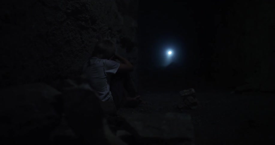 A person can be seen in a dark area shining a flashlight