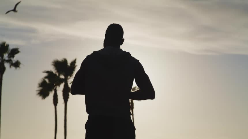 A man outside looks up at a bird flying