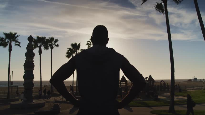 A man stands and watches people at a park