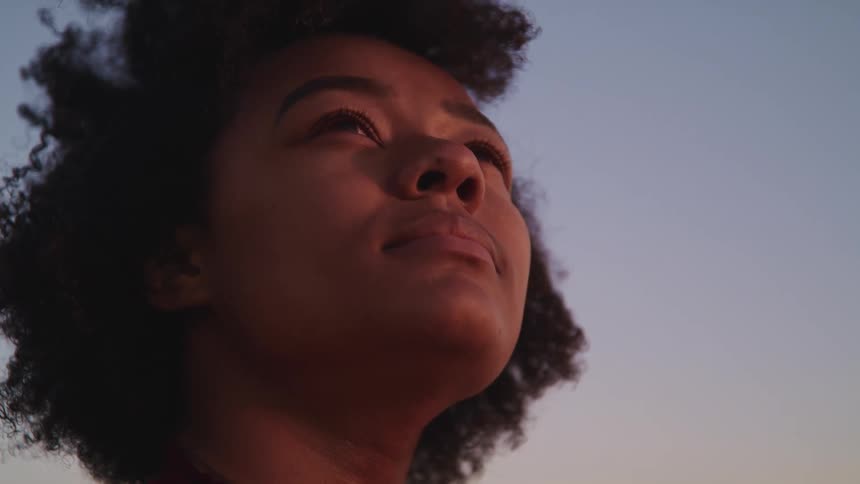 A woman is standing outside looking at the sunrise
