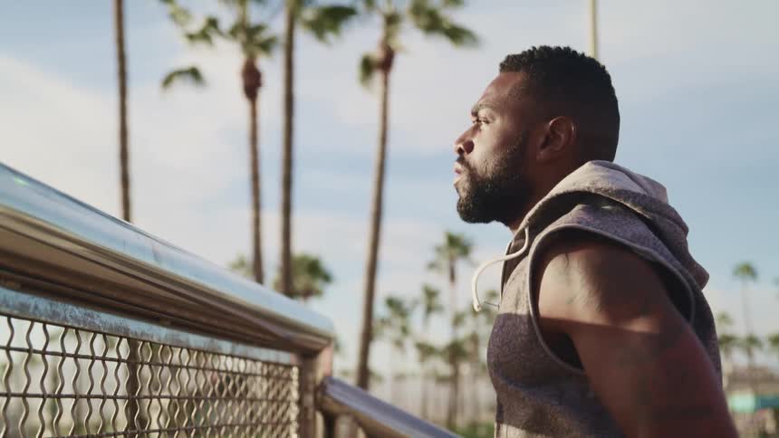 Young bearded man wearing sports clothes exercises near the railing on a park