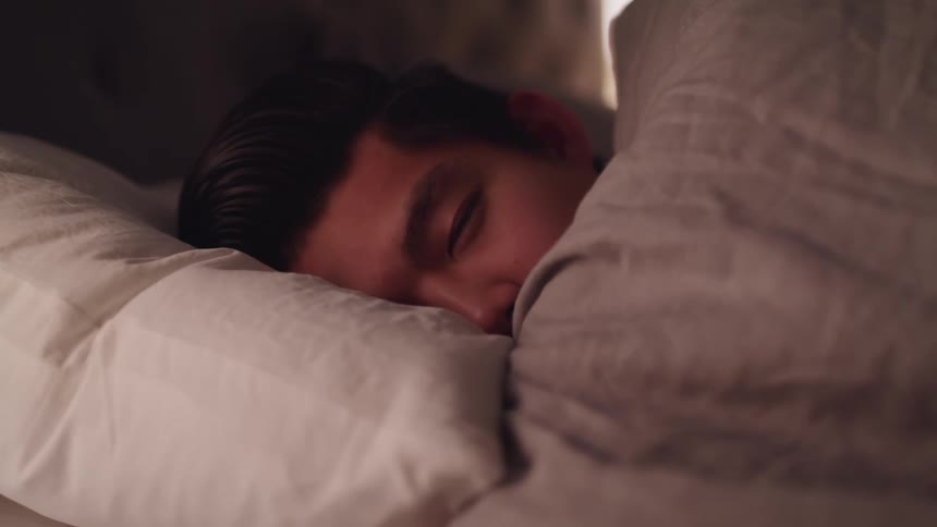 Asian man falls asleep in bed in bedroom
