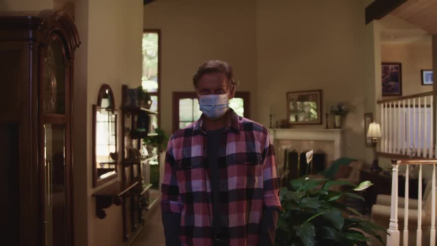 A man standing in a room wearing a mask