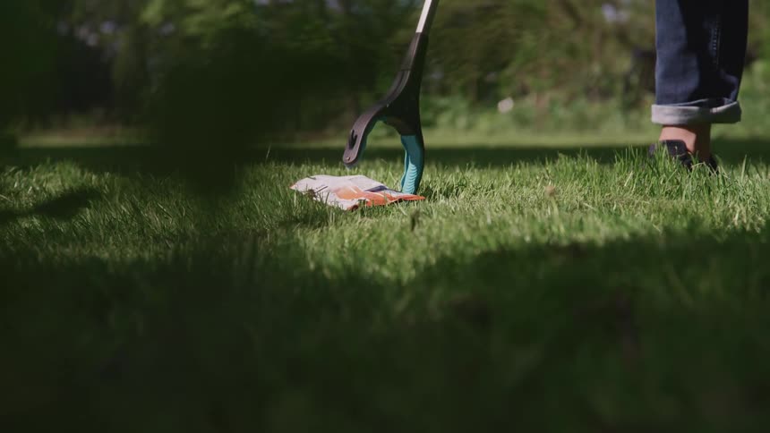 Person uses a tool to pick up trash from the grass