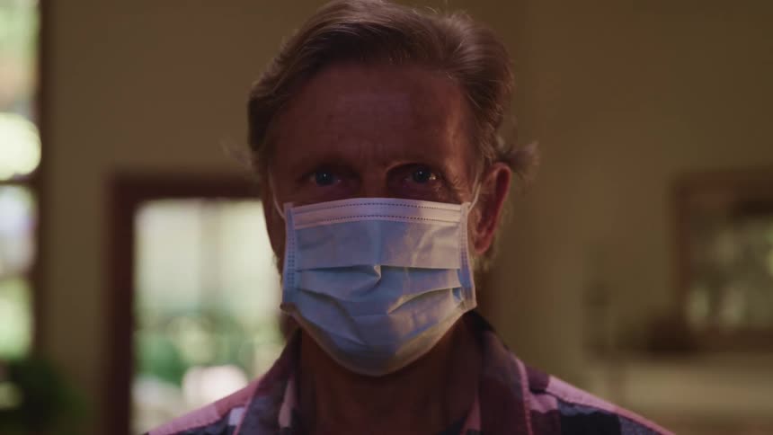 Man wearing face mask and collared shirt looks up