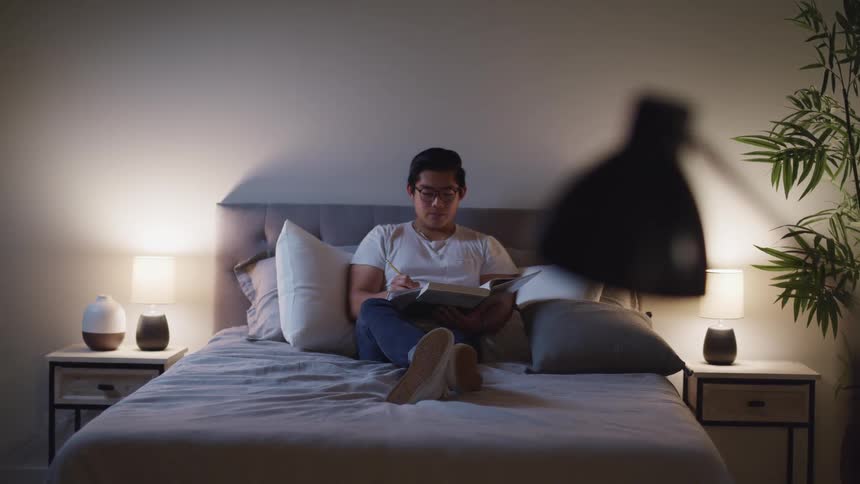 A man writes in his book laying on the bed