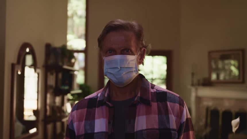 A man wearing a mask in his home