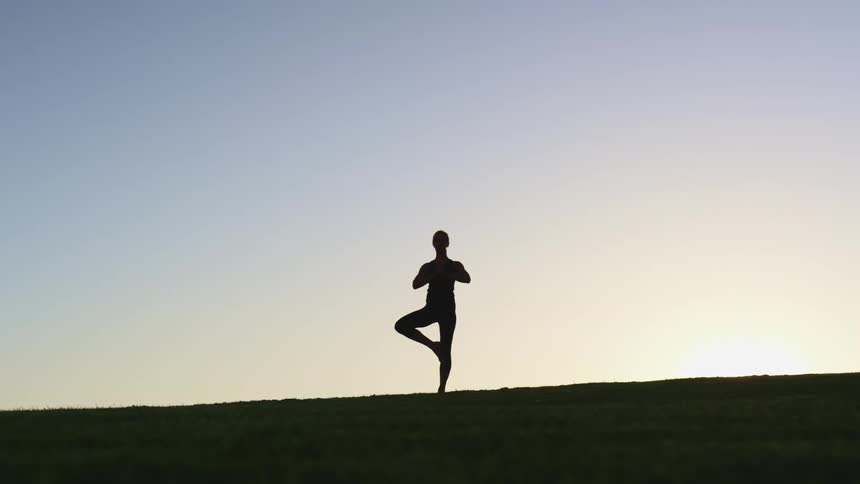 A woman holding a yoga pose outside