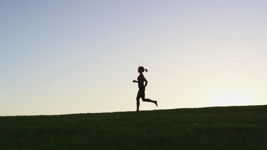 A woman is jogging outdoors at dusk