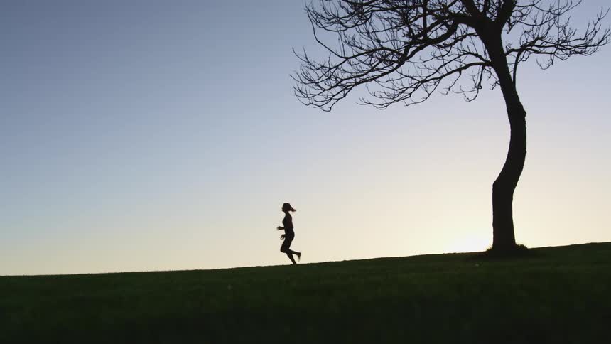 A woman running down a hill near a tree