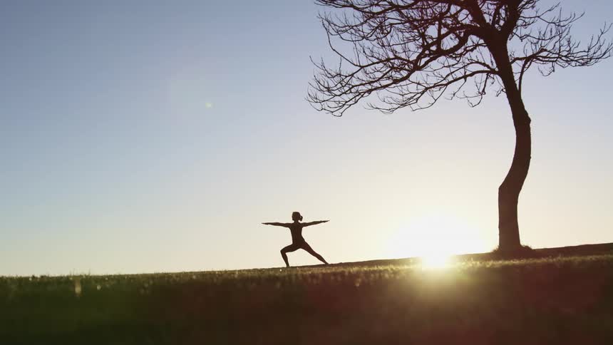 A woman doing yoga next to a tree