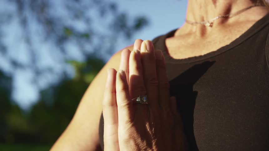 Close up of a woman with her palms together outdoors