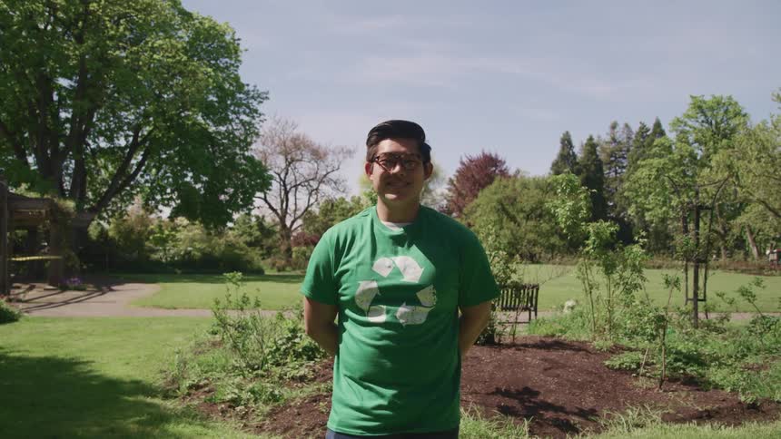 A teenage boy stands in a park and smiles