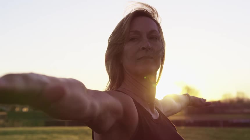 A woman is doing yoga at sunrise