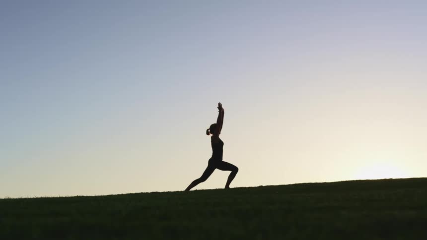 A woman is doing yoga at sunrise