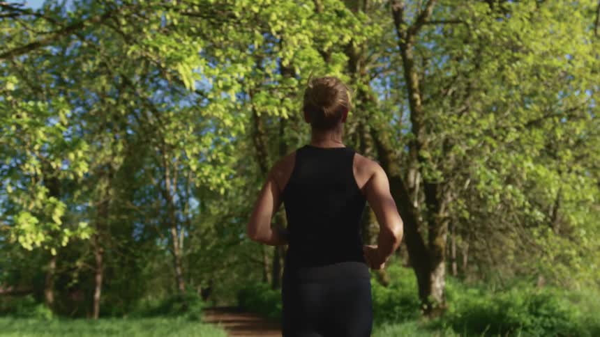 A woman running down a path in a wooded area