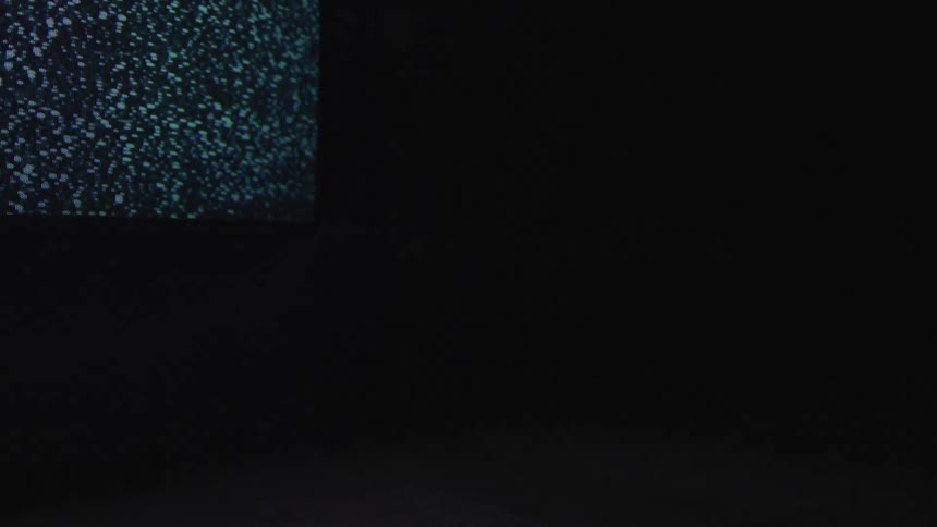 A television screen in the dark showing statics snow