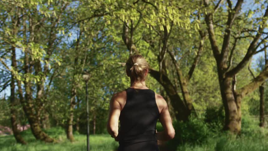 A woman running down a trail in a treed area