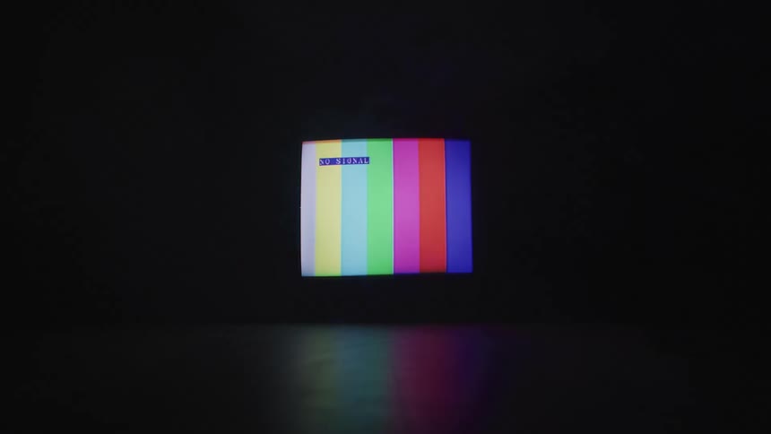 A television screen displaying colorful stripes flashes in a dark room