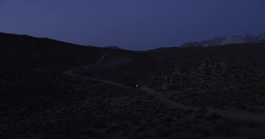 A vehicle drives on a dirt road in the wilderness