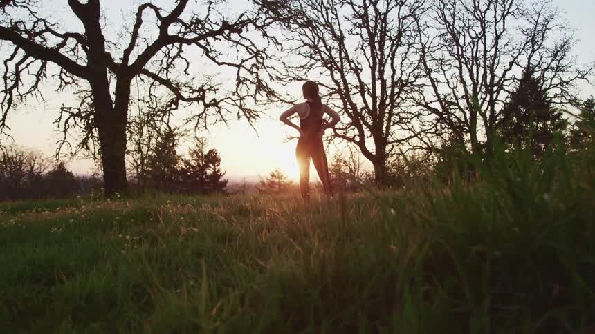 A woman stands and looks across the grassy landscape
