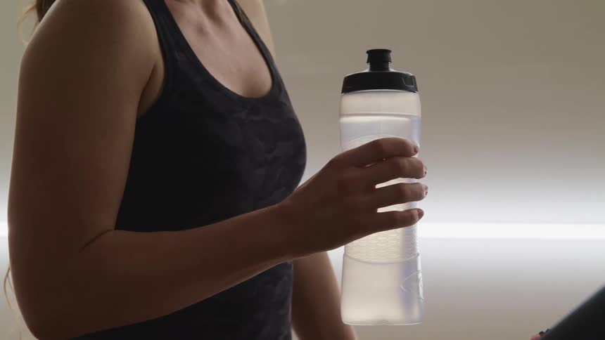 A female caucasian standing with a water bottle