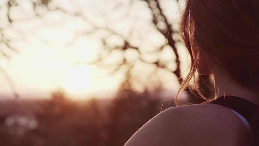 A woman is standing outside looking at the sunrise
