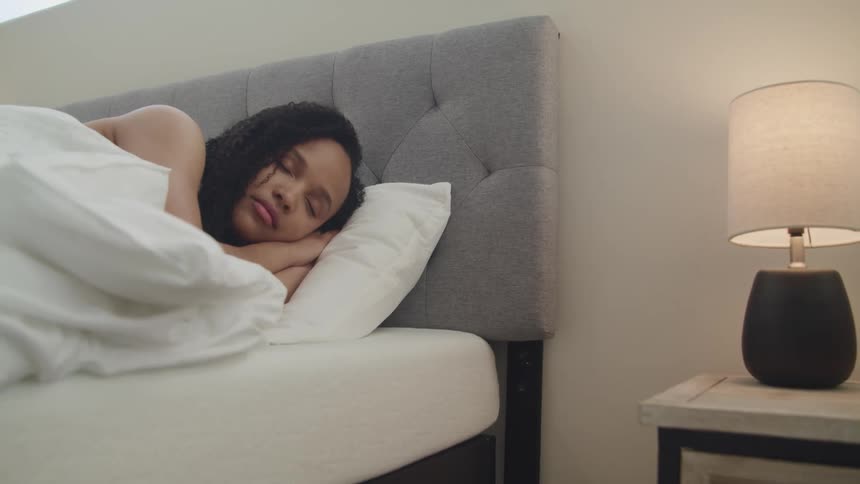 Black woman with curly hair lies in bed and falls asleep in the bedroom