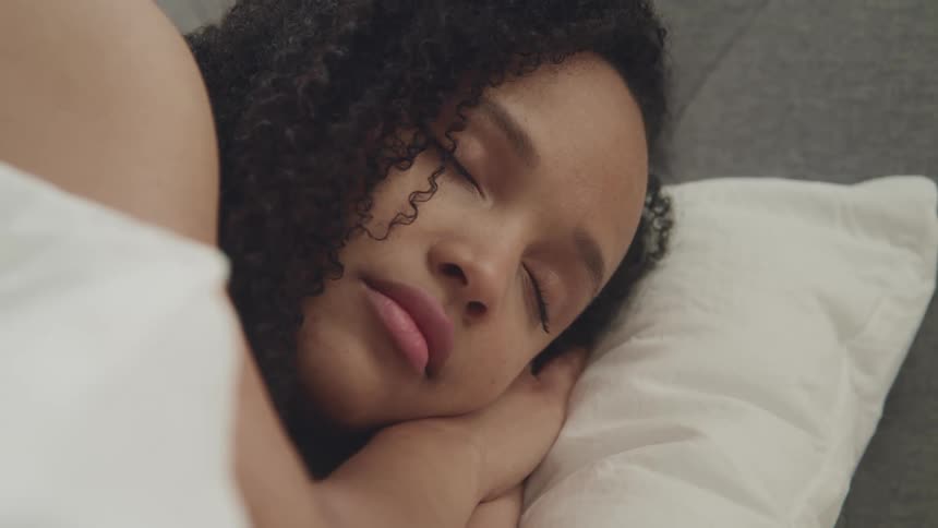 Woman with curly hair sleeps peacefully in bed