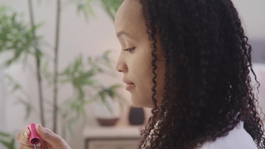 Female using mascara wand to carefully apply mascara to her top eyelashes