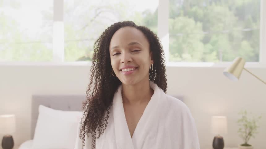 Black woman turns her head and smiles while wearing a white bath robe