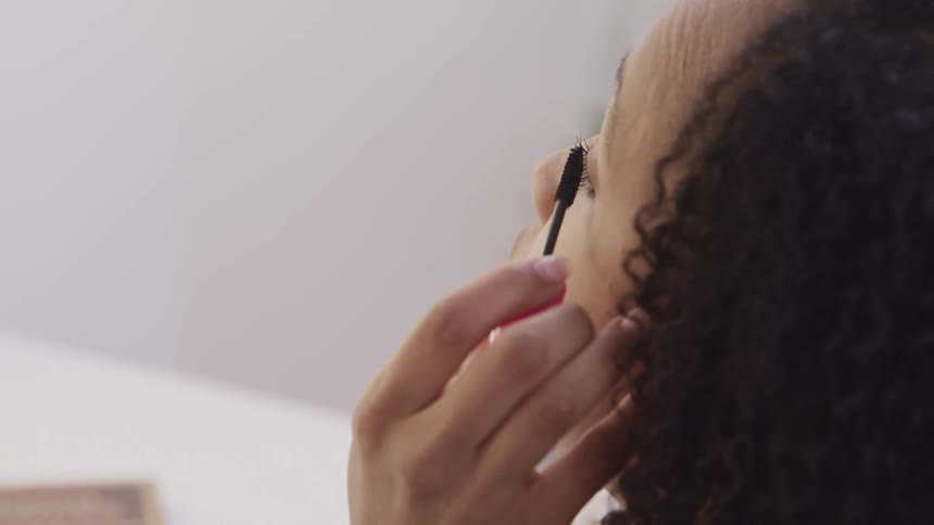 Close up of a woman applying makeup on her eyelashes at home