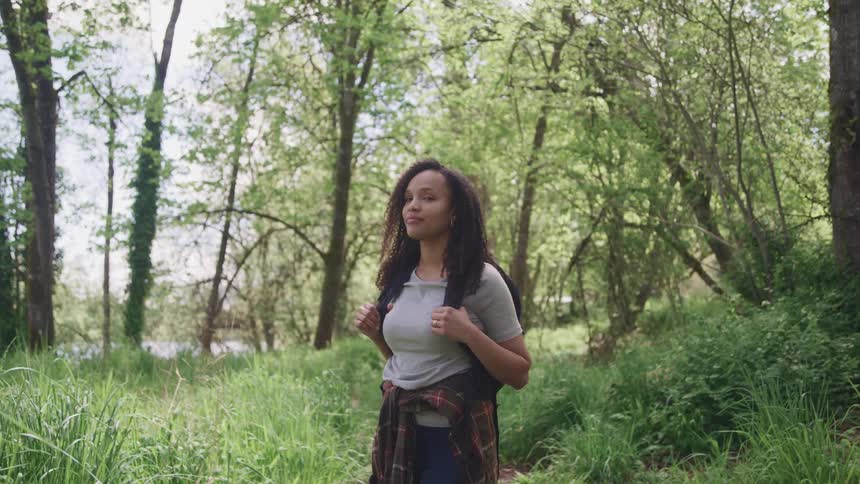 Woman wearing a backpack stands in a forest