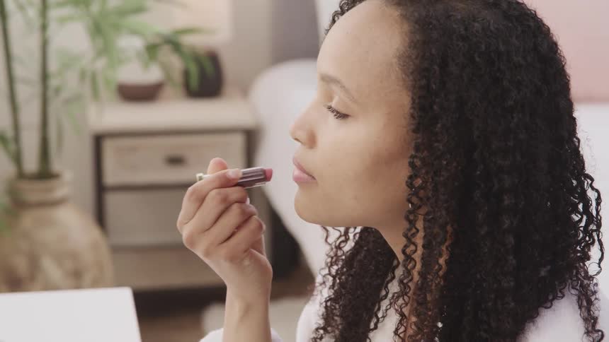 A woman is putting on lipstick