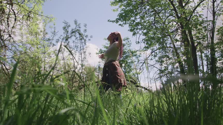A woman stretches her arms out as she stands in a field