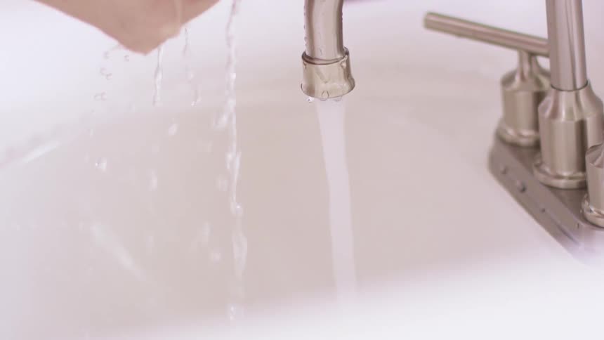 A woman washing at her sink at home