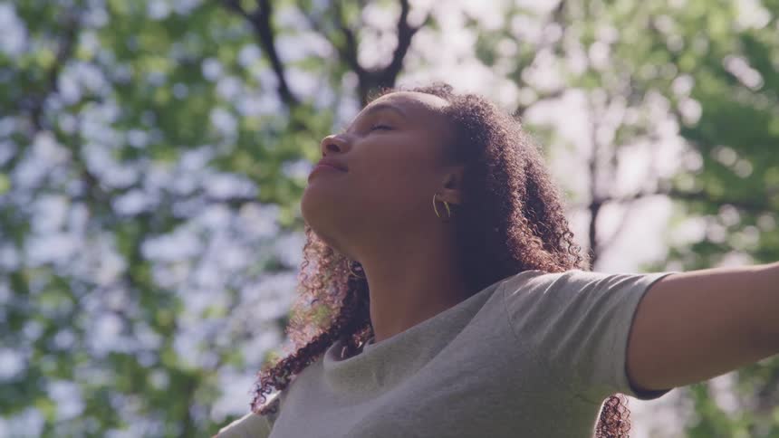 A woman is standing outside with her arms raised