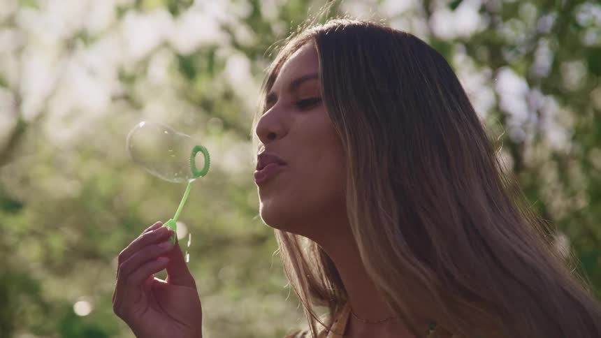 A woman blowing bubbles in a forest