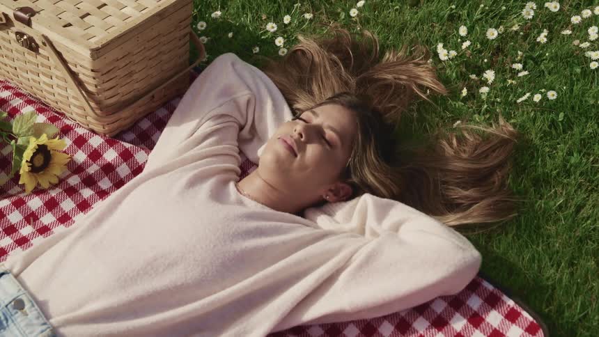 A teenager lying on a picnic blanket outside