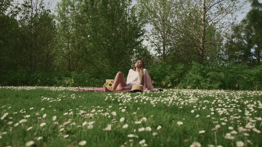 A woman sitting in a field on a blanket