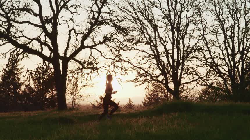 Woman jogging in a field at sunset
