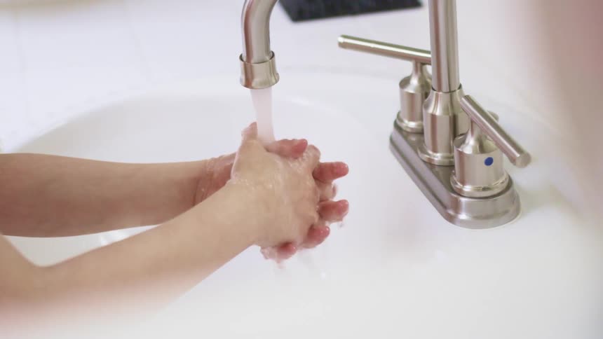 Girl puts her hands under the tap and washes her hands in the bathroom