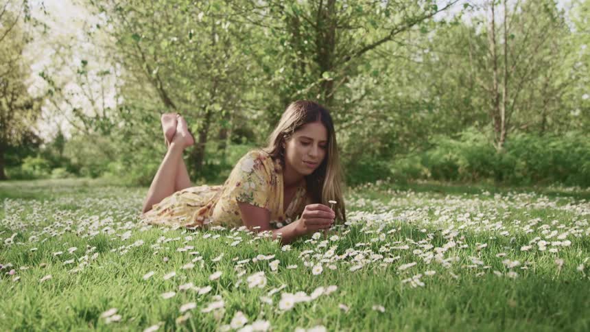 A woman laying in a field holding flowers