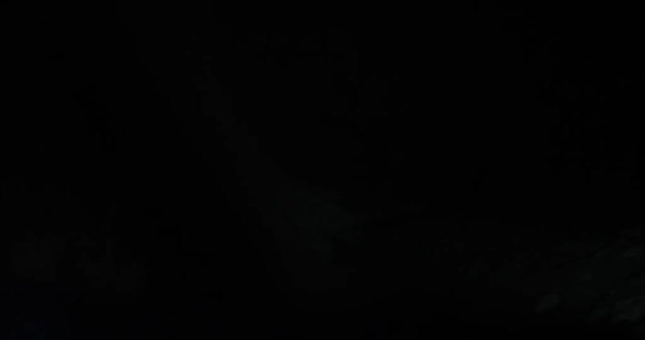 Walls and ceiling of a dark cave shown by flashlight