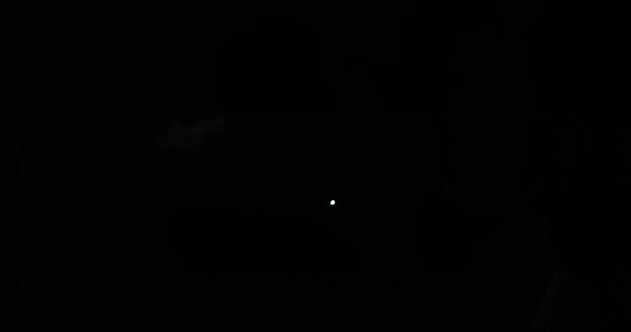 A person holding a flashlight is searching through a dark cave